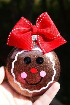 a hand holding a christmas ornament with a smiling face on it