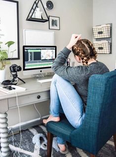 a woman sitting in a blue chair at a desk with a computer monitor and keyboard