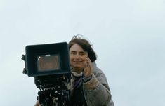 a woman holding a camera up to her face and making the peace sign with her hand