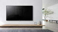 a large flat screen tv mounted on the wall in a living room with white walls