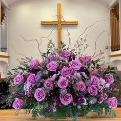 purple flowers are arranged in a vase on the alter