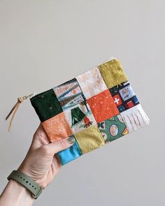 a hand holding up a small patchwork wallet