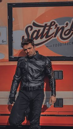 a man standing in front of a food truck with his hand on his hip and wearing a leather jacket