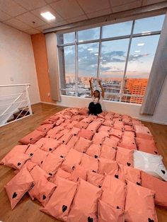 a person sitting on top of a bed made out of pink sheets with black hearts