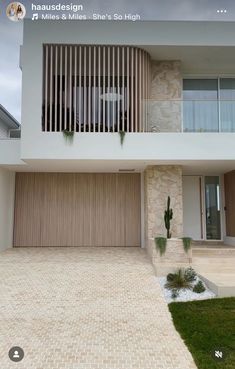 a house that is in the middle of a driveway with grass and plants on it