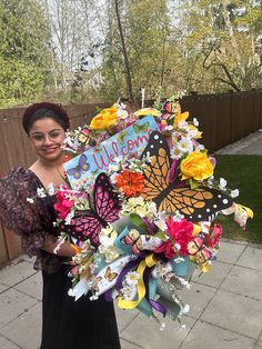 a woman is holding a bouquet of flowers and butterflies with the word welcome written on it