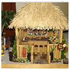 a tiki hut made out of bamboo sticks and grass with flowers on the roof