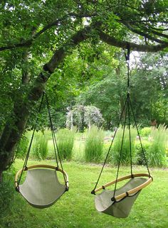 two hammocks hanging from trees in the grass