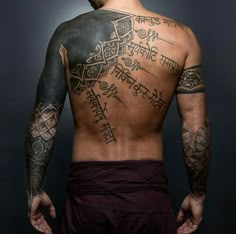 a man with lots of tattoos on his back and chest is standing in front of a dark background