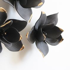 three black flowers on a white surface