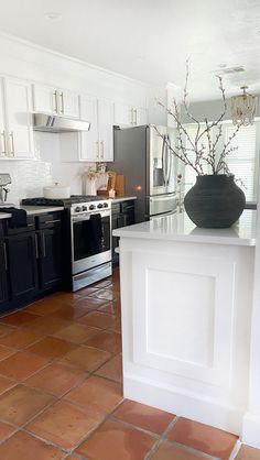 a kitchen with black and white cabinets, an island countertop and tile flooring