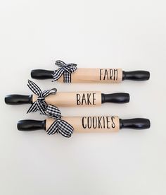 three wooden utensils with black and white ribbon tied around the handles that say fart bake cookies