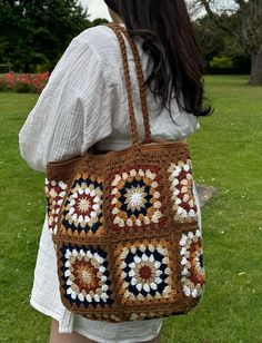 a woman carrying a crocheted bag in the grass