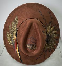 Made from premium faux suede with cotton and leather banding. She has all the western elements making her wild and bold! I use only the best materials for my hats and each one is handcrafted and uniquely one of a kind.  This hat has an adjuster inside the crown that allows 22-24.5 inch circumference; she fits most sizes. Brim length - 3.75" Height - 4.72" Due to the nature of my hats and because of various sanitary concerns, hats are NOT returnable or exchangeable. All sales are final. Brown Felt Hat For Rodeo In Fall, Brown Felt Hat For Fall Rodeo, Handmade Brown Hat For Festival, Bohemian Brown Felt Hat For Festival, Custom Brown Hat Bands For Ranch, Bohemian Gold Hat Bands For Country Events, Brown Country Style Fedora For Ranch, Country Style Brown Fedora For Ranch, Brown Felt Hat For Country Events