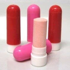 three pink and one red lipsticks on a white surface with the caps slightly down