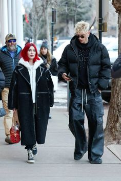 two people walking down the street with one person wearing a black coat and white shirt