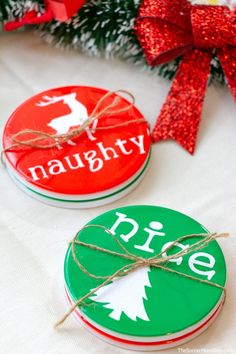 two red and green christmas coasters sitting on top of a white cloth covered table