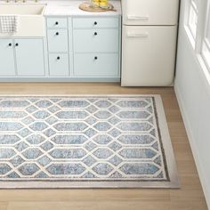 a kitchen with blue cabinets, white appliances and an area rug in the middle of the floor