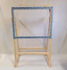 a wooden easel with blue tape on the top and bottom frame, against a white background