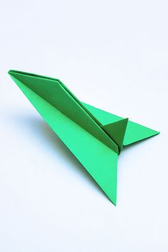 an origami green paper airplane on a white background