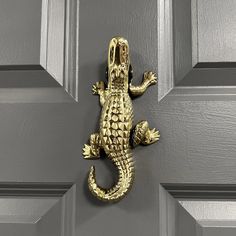 a gold alligator door knocker on a gray front door