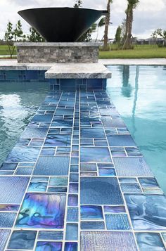 an artisticly designed swimming pool with blue glass tiles on the floor and in the water