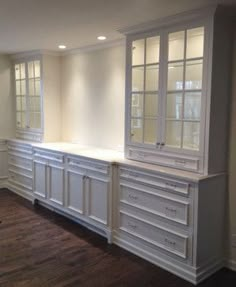 an empty room with white cabinets and wood floors