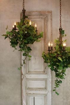 two hanging planters filled with green plants next to a white door and light fixture