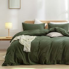 a bed with green sheets and pillows in a room