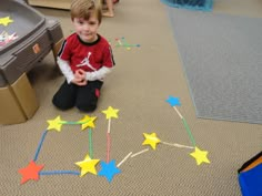 a young boy sitting on the floor playing with stars