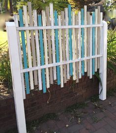 a white picket fence with blue slats on the top and bottom, next to a brick wall