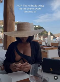 a woman sitting at a table with a wine glass and cell phone