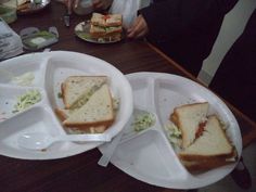 two plates with sandwiches on them sitting on a table