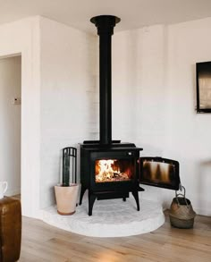 a living room with a fire place in the corner and wood burning on the stove