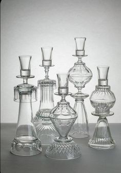 an assortment of glass vases and candlesticks are shown in black and white