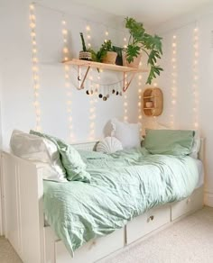 a bed with green sheets and pillows in a room decorated with string lights, potted plants and other decorations