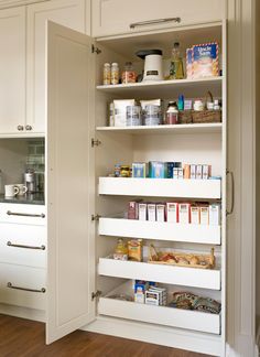 an open pantry door in a kitchen with white cabinets and wood flooring on the side