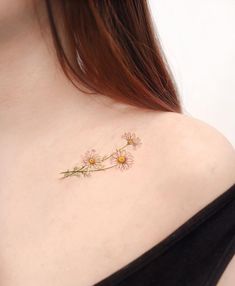 the back of a woman's shoulder with daisies on it