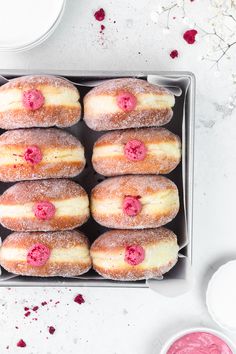 a box filled with donuts covered in powdered sugar and raspberry toppings