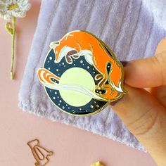 a hand holding a pin with an orange fox on it