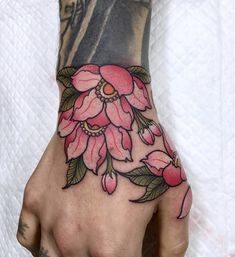 a woman's hand with pink flowers and leaves tattooed on the left side of her arm