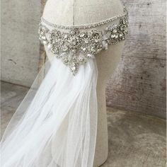 the headpiece is adorned with crystal beads and white tulle, along with a veil