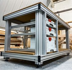 an open refrigerator sitting inside of a metal structure in a building with lots of wood planks