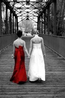 two women in dresses walking down a bridge holding hands and looking at each other's backs