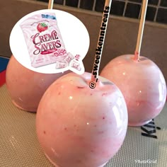 two pink apples sitting on top of a table next to a bag of creme