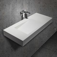 a white sink sitting on top of a counter next to a wall mounted faucet