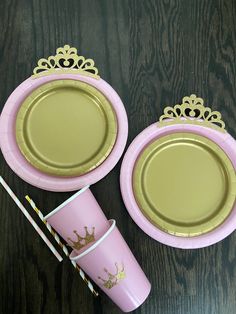 two pink plates with gold crown designs on them, one has a straw in it