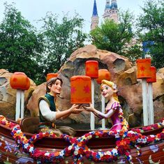 two people dressed as disney characters in front of a fake castle with flowers on it