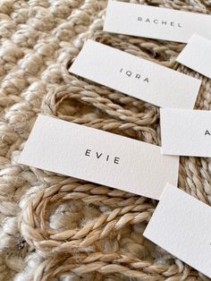 four white name tags sitting on top of a pile of woven material next to each other