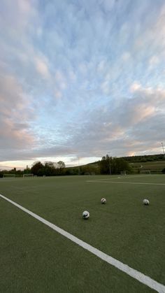 three soccer balls sitting on top of a green field